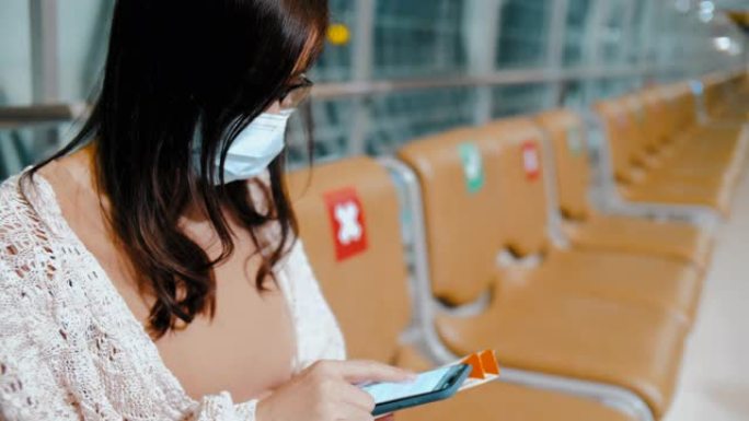 在机场航站楼使用智能手机的年轻亚洲妇女