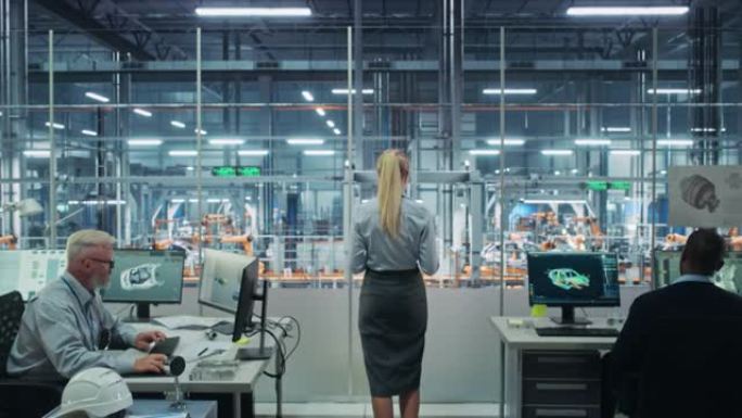 汽车厂办公室: 成功的女总工程师俯瞰自动化机器人手臂装配线制造先进的高科技电动汽车。生产输送机。后视