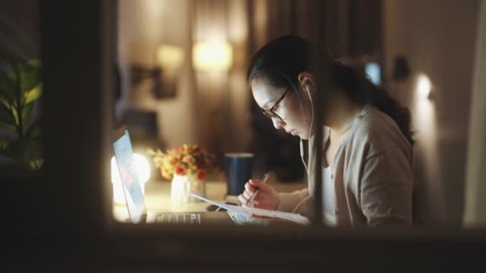 亚洲妇女在家里晚上用笔记本电脑工作