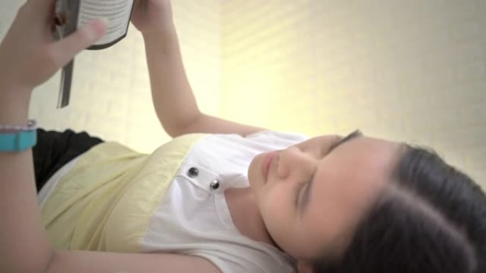 美丽的亚洲女孩睡前在卧室看书