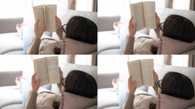 女人在家客厅看书翻阅躺在沙发上窗外