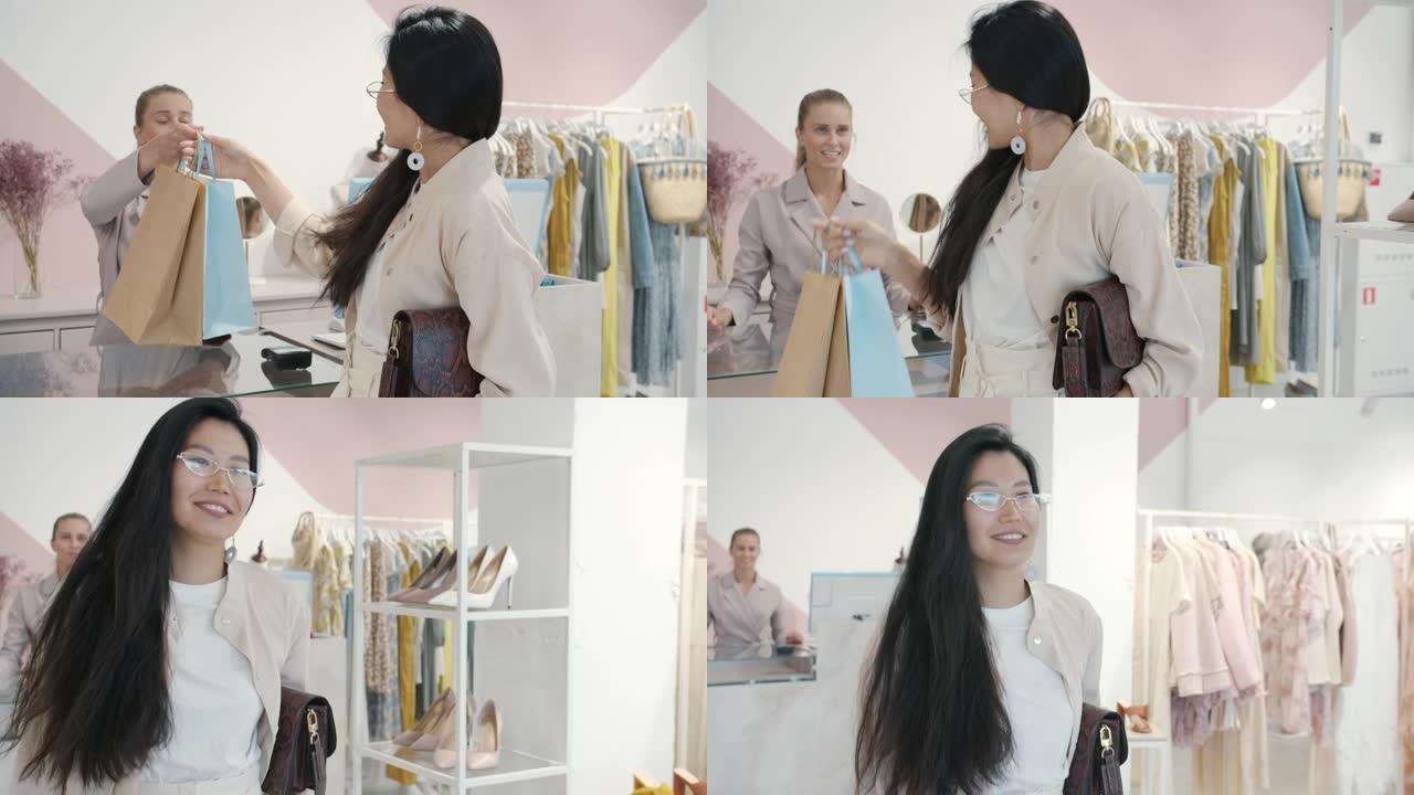 快乐的亚洲女人从店员那里拿购物袋走路的慢动作