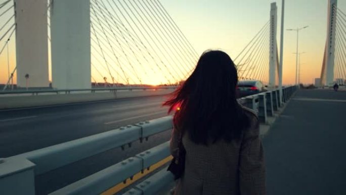 女人在日落时在桥上走开