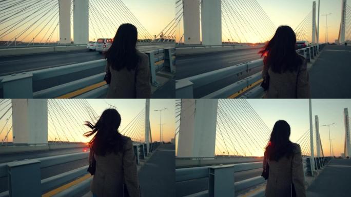女人在日落时在桥上走开