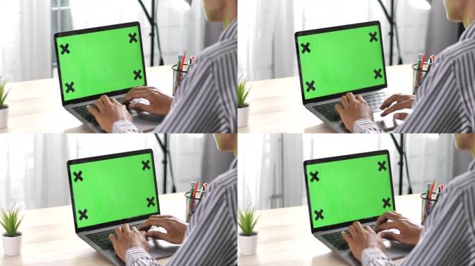 男人坐在带有绿色色度键屏幕的笔记本电脑前