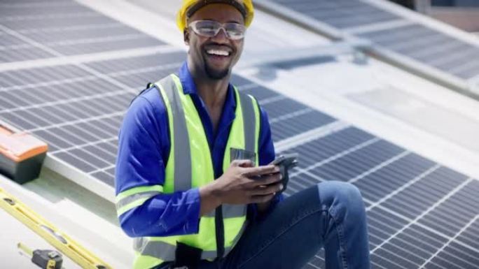一个快乐的年轻人在建筑物的屋顶上安装太阳能电池板时使用智能手机，一个微笑的男人在可再生能源建筑项目中