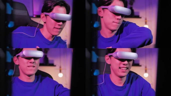 在晚上在彩色紫外线照明客厅的VR体验中，戴着虚拟现实耳机和手势的亚洲年轻人的获胜者坐在办公桌前并与操