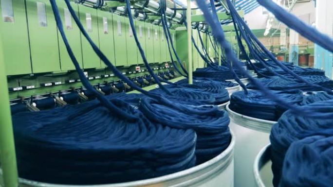 纺织厂生产设备。彩色纱线正在从桩上机械地解开