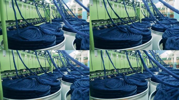 纺织厂生产设备。彩色纱线正在从桩上机械地解开