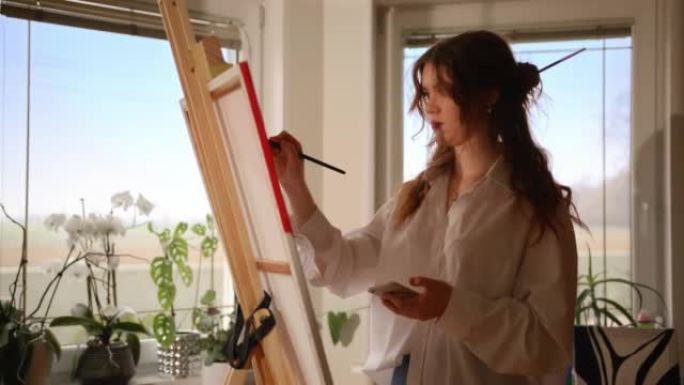 一位年轻女艺术家在画布上复制颜料的SLO MO肖像