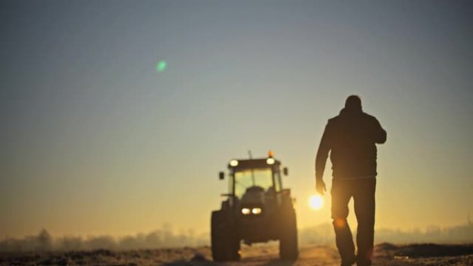男性农民在日出时走向农田拖拉机