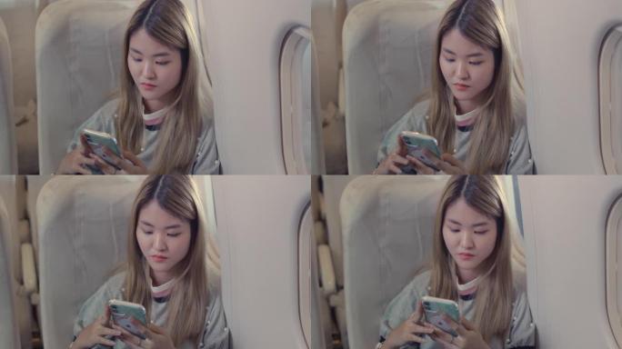 亚洲女性乘客晚上在飞机上使用智能手机