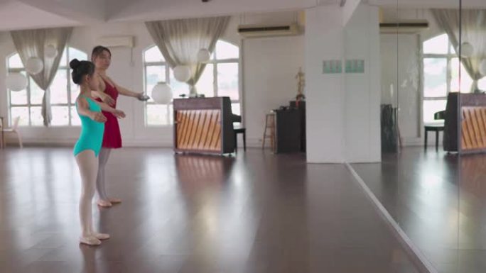 亚洲中国少女芭蕾舞演员面对镜子在工作室训练她的年轻女学生