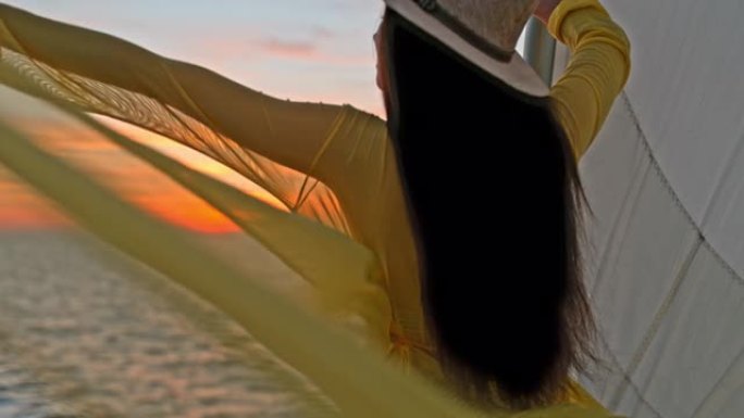 超级SLO MO年轻女子享受日落时帆船船头的微风