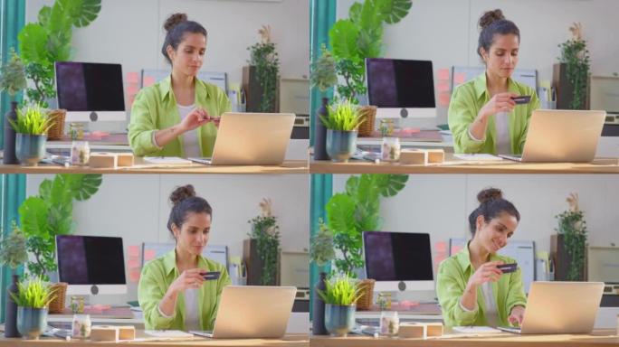 女人经营生意在家做蜡烛，用笔记本电脑上的信用卡在线购物-慢动作拍摄