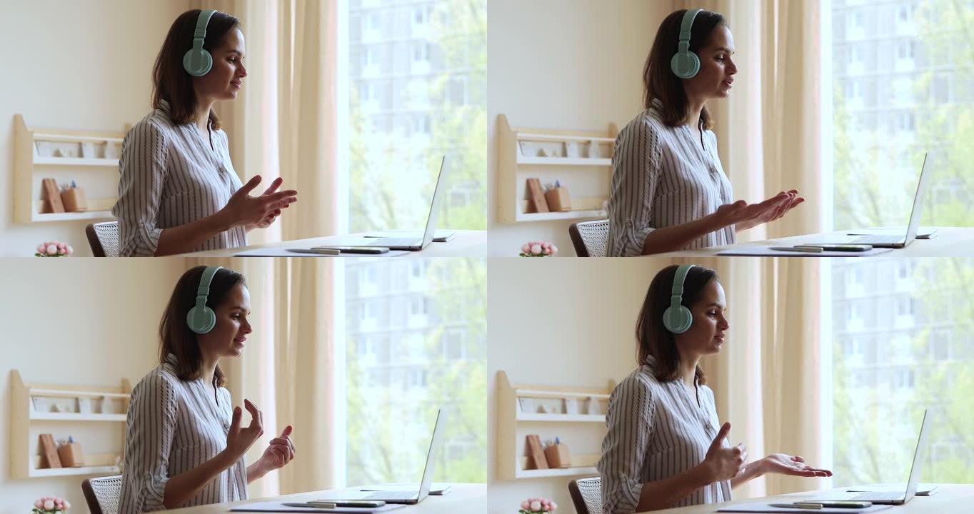 愉快的年轻女性戴耳机使用笔记本电脑与顾客交谈