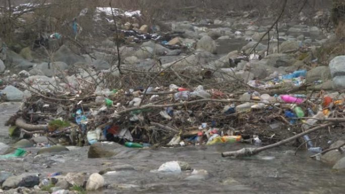 静态镜头: 流动的河流被杂物和塑料垃圾包围