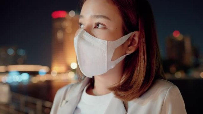 亚洲女性在城市夜晚戴防护口罩。