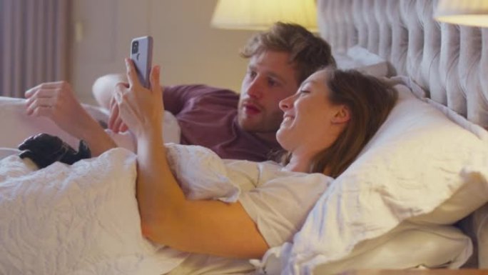 夫妻在床上与假肢的女人一起看着手机-慢动作拍摄