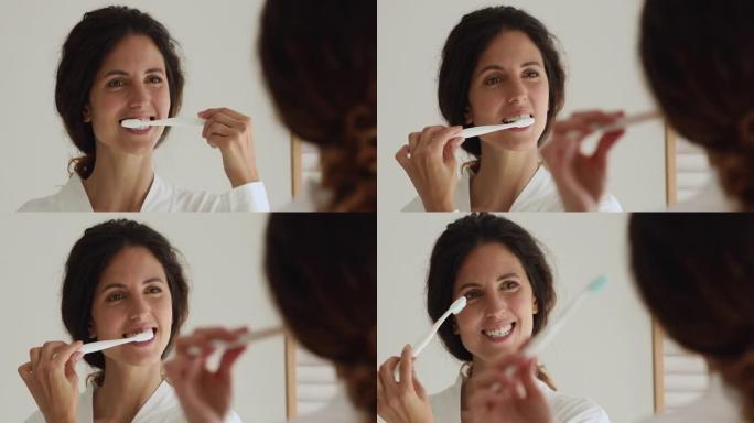 迷人的女人刷牙时照镜子