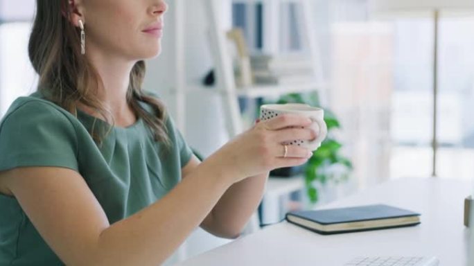 4k视频片段，一位年轻的女商人在现代办公室中使用计算机时喝咖啡