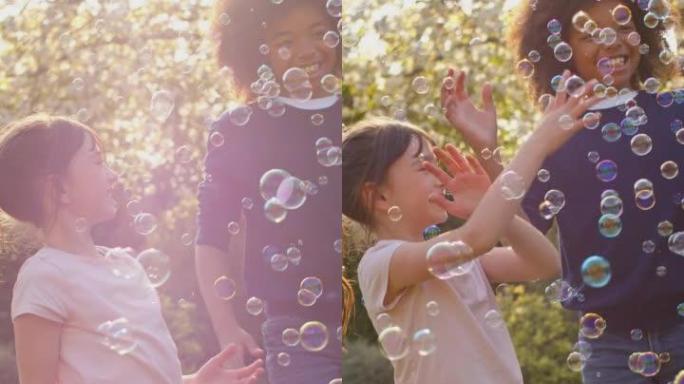 微笑的男孩和女孩在户外玩花园泡泡的垂直视频 -- 慢动作拍摄