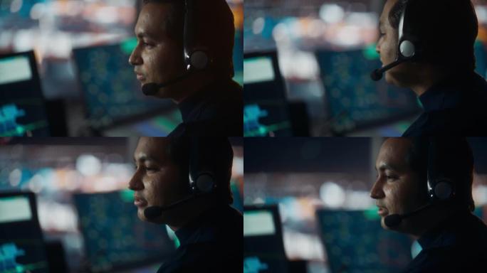 在机场塔楼的电话中，用耳机通话的男性空中交通管制员的特写肖像。办公室里满是台式电脑显示屏，配有导航屏