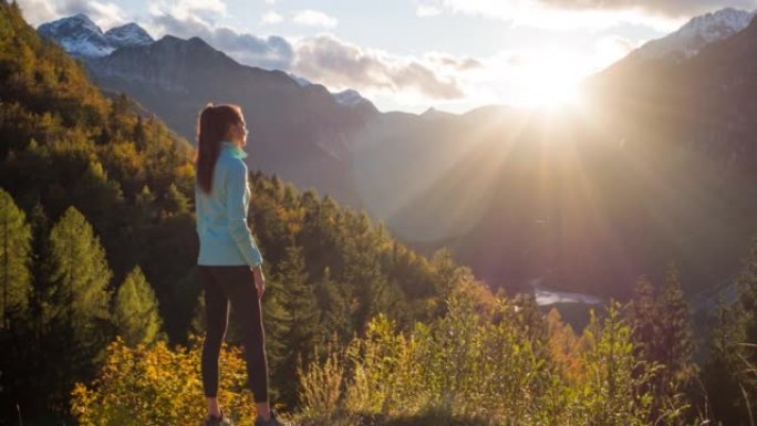 健康导向的女人站在山边，欣赏山谷湖泊和周围群山的壮丽景色