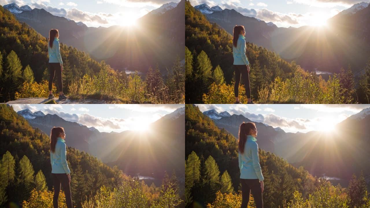 健康导向的女人站在山边，欣赏山谷湖泊和周围群山的壮丽景色