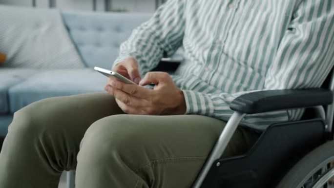 坐在轮椅上的残疾人在家里使用智能手机触摸屏进行慢动作