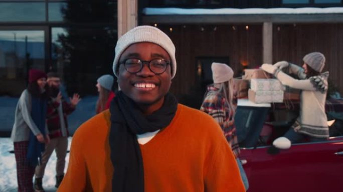 年轻快乐兴奋的非洲裔美国男子穿着冬装在有趣的圣诞朋友派对慢动作中对着镜头微笑。
