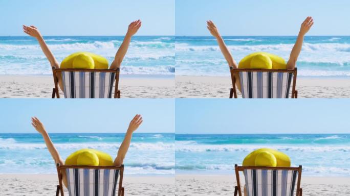 一个兴奋的女人从后面在海边的沙滩椅上放松。开朗的女性在暑假和热带度假胜地享受自由