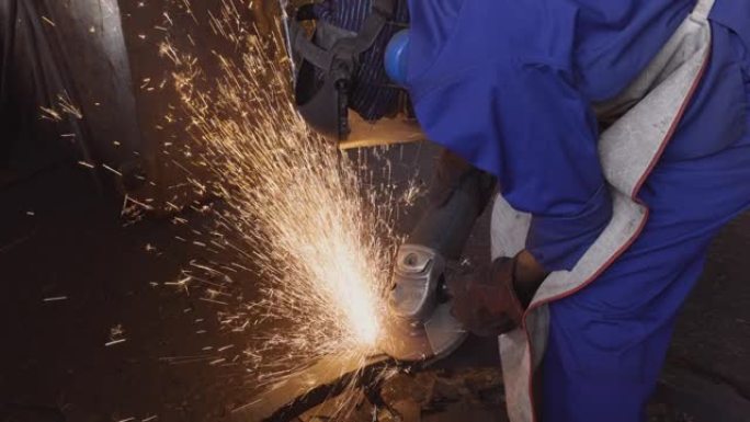 工厂工人使用研磨机研磨在铸造厂铸造的钢制零件上的粗糙边缘