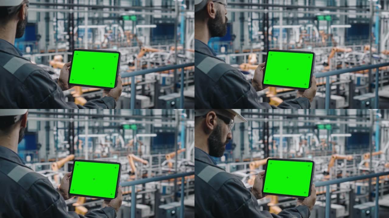 汽车工厂工程师在工作制服中使用带有绿屏模型显示的平板电脑。汽车工业制造工厂从事汽车生产的增强现实软件