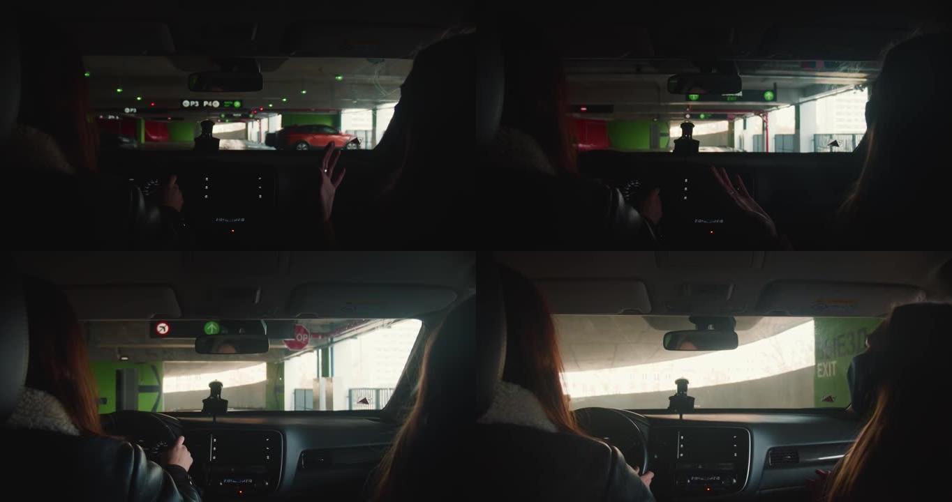 POV从车内拍摄。两名妇女在沿着黑暗的停车场驾驶私人车辆时交谈，灯光驶向出口。
