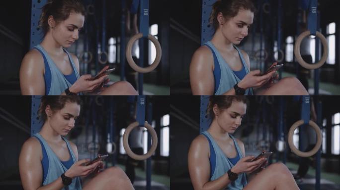 健身生活方式应用程序。美丽的运动员女人使用智能手机在现代健身房锻炼后跟踪身体活动。