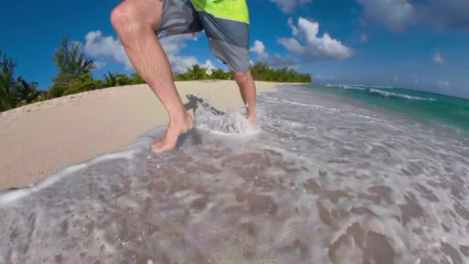 低角度: 无法识别的男性游客赤脚沿着热带海滩奔跑。