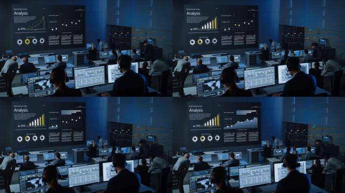 在现代监控办公室工作的专业交易员的动态镜头，在大屏幕上显示实时分析供稿。监控室经纪人和财务专家坐在电