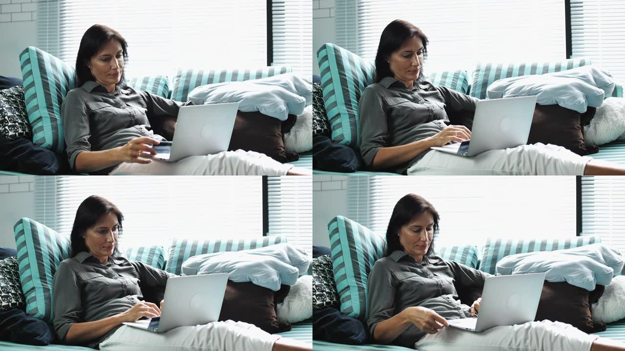 女人坐在沙发上在家使用笔记本电脑