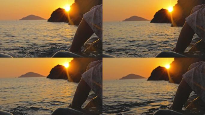 日落时在水中玩脚的女人的慢动作视图。