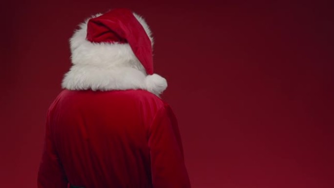 转过身来的圣诞老人在红色背景上竖起大拇指