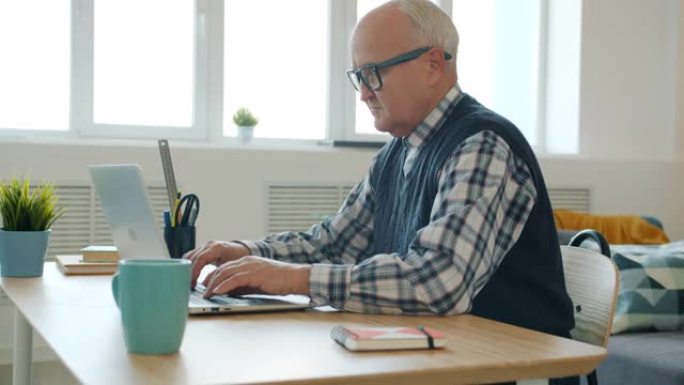 认真的退休男子在家里用笔记本电脑工作，忙于自由职业者的慢动作