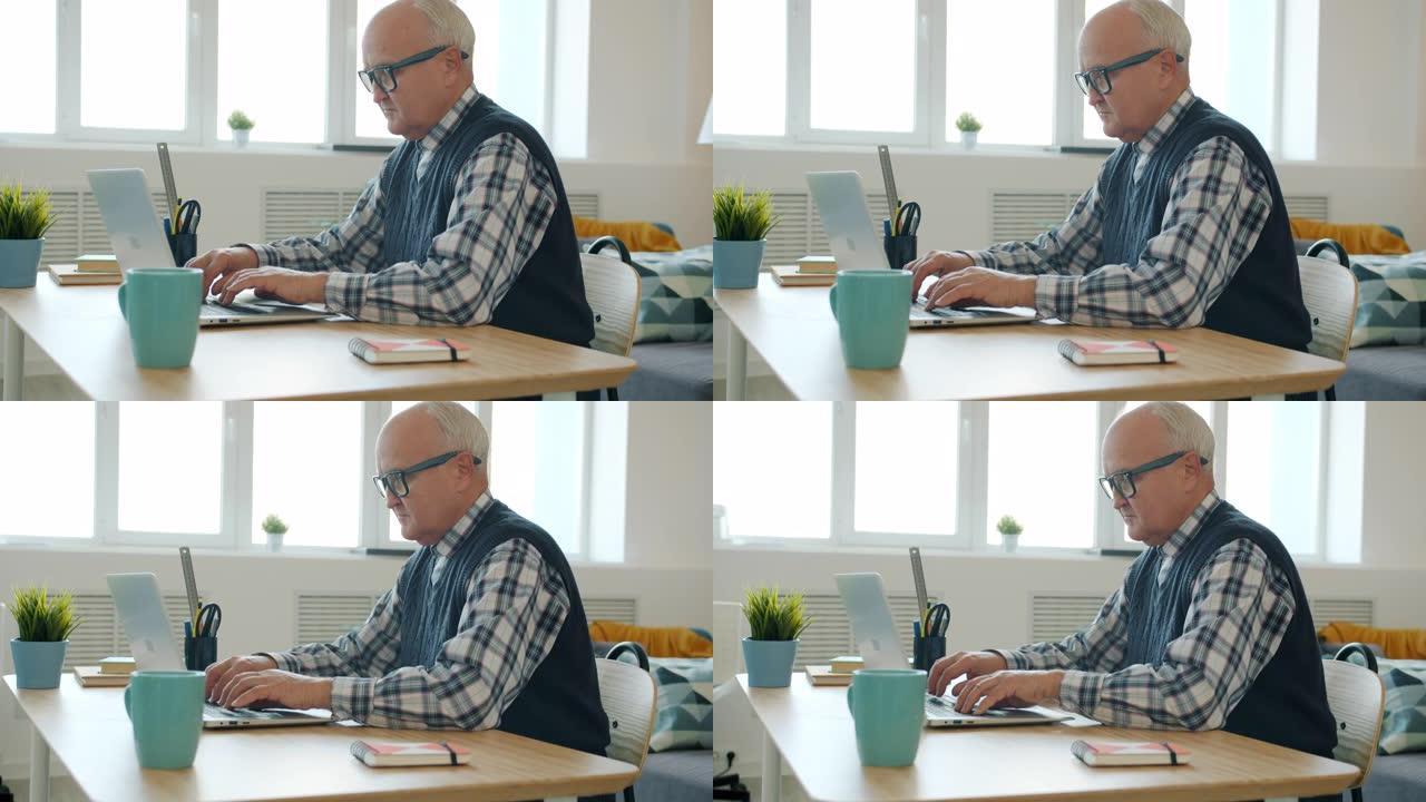 认真的退休男子在家里用笔记本电脑工作，忙于自由职业者的慢动作