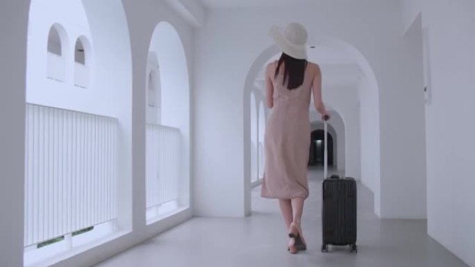 一个提着行李箱走在酒店走廊上的女人