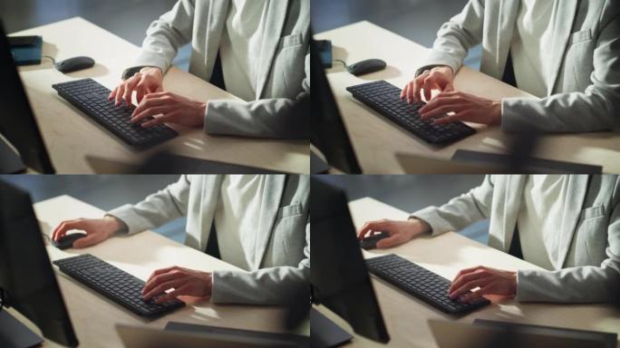 白天，穿着灰色休闲夹克的年轻男性员工在办公室的计算机上工作，靠近经理的手，在键盘上键入文本，编写文本
