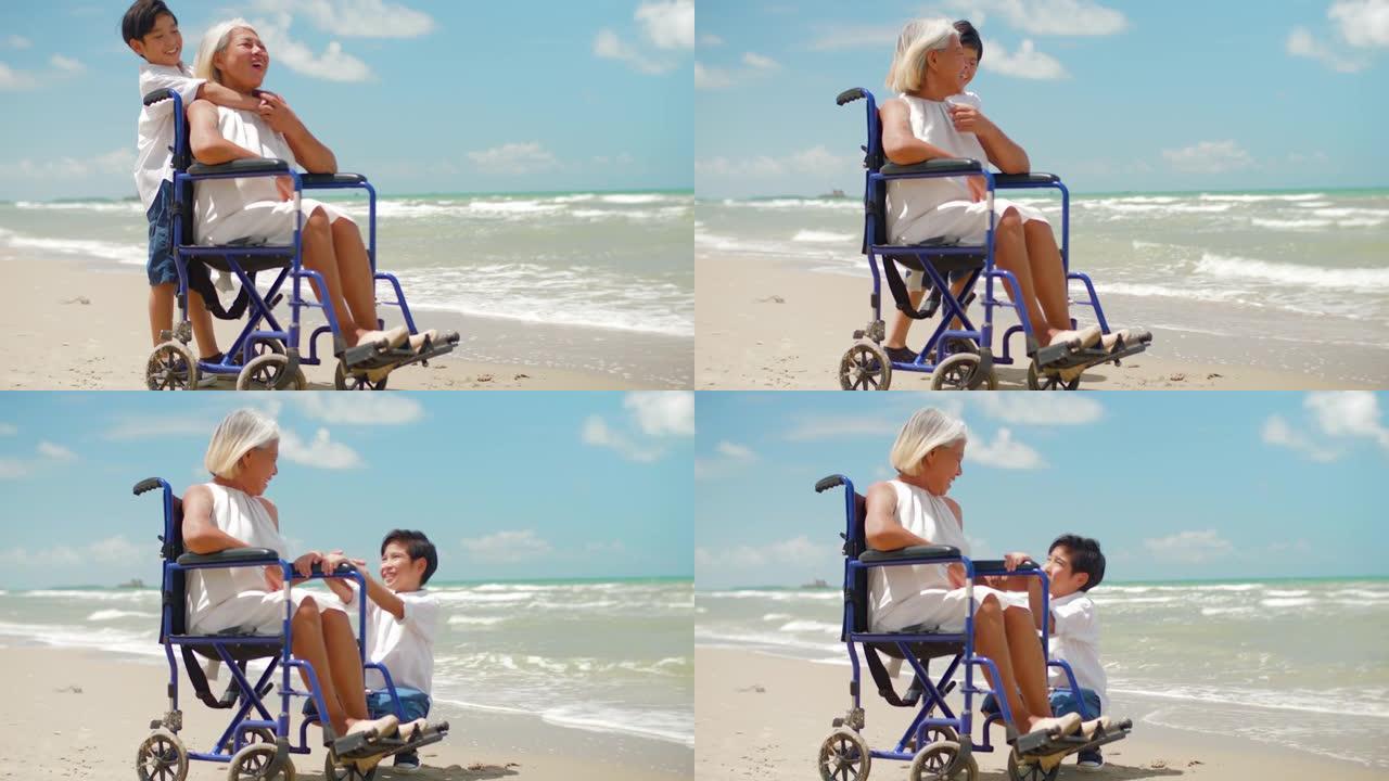 资深亚裔女子与孙子坐在沙滩上轮椅