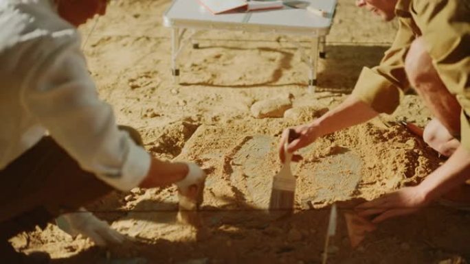 考古挖掘现场: 两位伟大的考古学家在挖掘现场工作，仔细清理，举起新发现的古代文明文化文物，历史悠久的