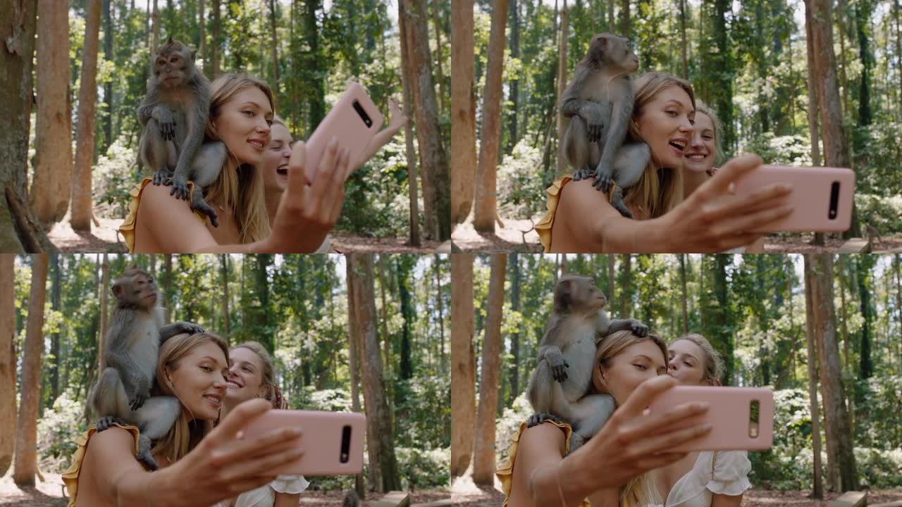 两名妇女使用智能手机拍摄猴子坐在肩膀上的照片女孩朋友在野生动物动物园与猴子合影，游客在巴厘岛旅行