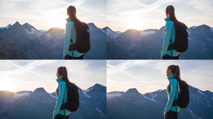 年轻的女徒步旅行者站在山顶上，在日落时欣赏壮丽的景色