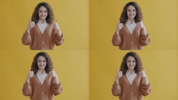 黄色背景上激动的年轻女子用竖起大拇指的手势微笑的肖像